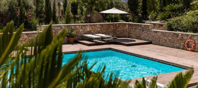 A blue pool with two sun bathing chairs