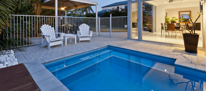 A swimming pool and two Adirondack chairs