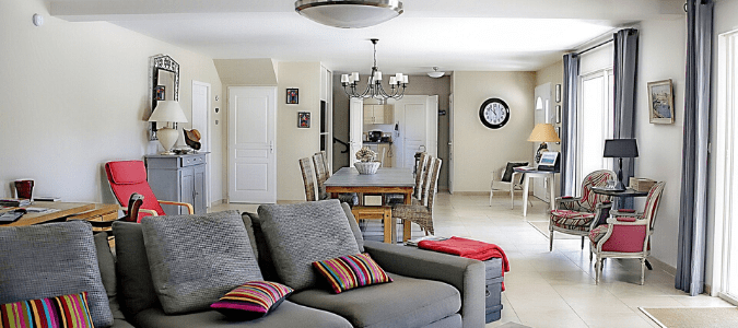 A living room with a gray, reclining couch and red pillows