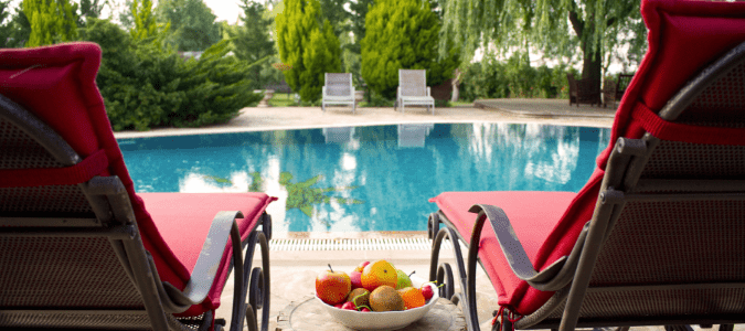 Two red lounge chairs next to a clear pool