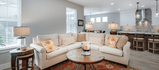 A living room that looks into a gray kitchen