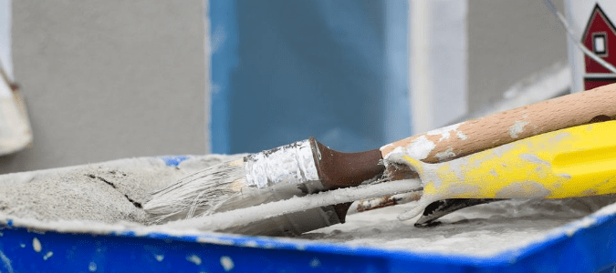 A roller and a paintbrush that have been gathered to paint trim in a carpeted room