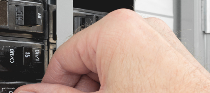 a hand flipping buttons in a breaker box